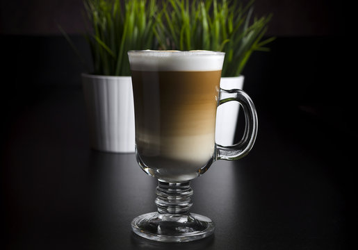 Coffee latte in a glass with green grass on the background