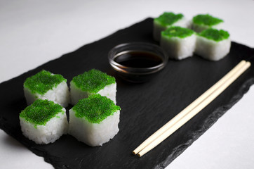 Green sushi on slate plate with bamboo sticks