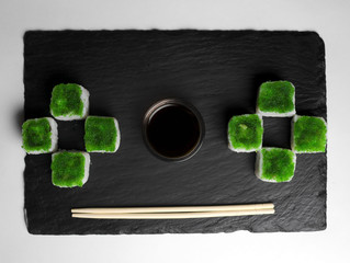 Green sushi on slate plate with bamboo sticks