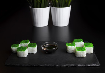 Green sushi on slate plate with bamboo sticks