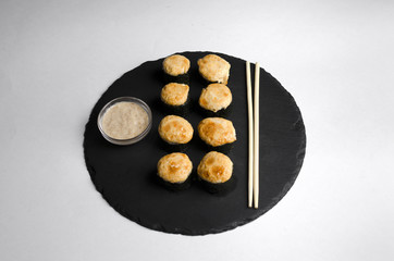 Baked sushi on slate plate with chopsticks