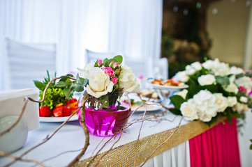 Flowers on vase with pink water at table of newlyweds.