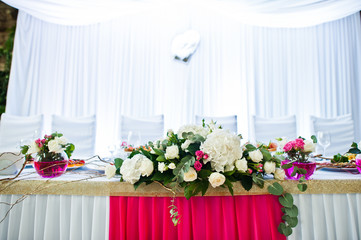 Flowers on vase with pink water at table of newlyweds.