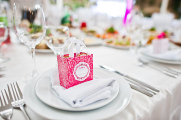Small pink box with candies at table on dish of wedding guest.