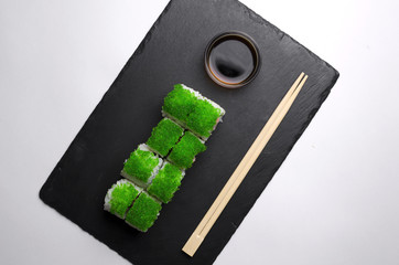 Green sushi on slate plate with bamboo sticks