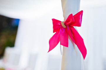 Small pink bow with brooch at wedding arch.