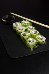 Green sushi on slate plate with bamboo sticks