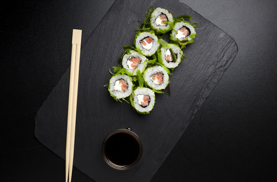 Green sushi on slate plate with bamboo sticks