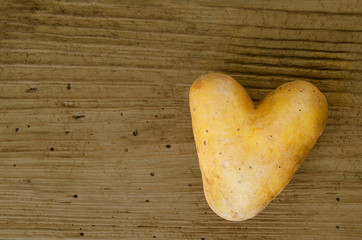 Heart shaped potato on an old spruce wood board from the sixteenth century with many wormholes....