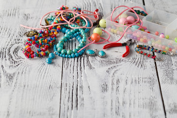 Assembly of jewelry of polymer clay in bohemian style with box with small beads. Hobby, handicraft. Pliers with unfinished necklace.
