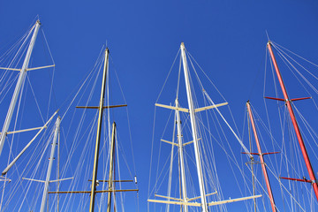 Bottom view of masts of yachts and sail boats with clear blue sky background in Bodrum marina.