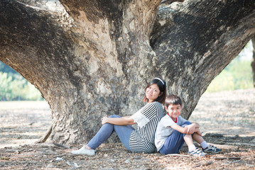 Mother and son sitting together under the tree
