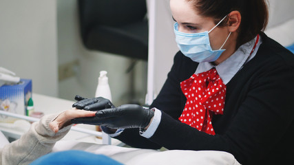 Closeup shot of a woman in a nail salon receiving a manicure by a beautician with nail file.