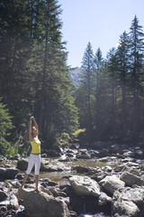 femme se relaxant les bras en l'air en été au bord d'une rivière