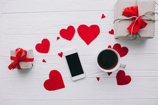 valentines day love letter on white wooden background with smart phone  and presents