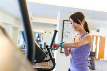 Sport Woman training on Elliptical machine and using smart watch