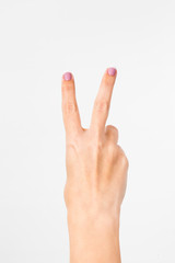 Closeup of female caucasian hand showing victory sign  isolated on white background. Young woman shows 2 fingers while counting. Nails with french pink manicure. Vertical color image