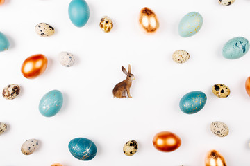 Easter bunny on white background decoration quail, gold and blue easter eggs with copy space for text. Flat lay, top view. Easter concept.