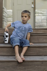 Naklejka premium Stylish boy in jeans sitting on stairs with portable radio