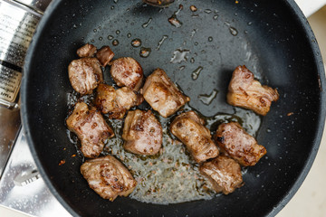 Chef Fried Marinated Diced Raw Beef in Pan with Rosemary Oil with Spoon.