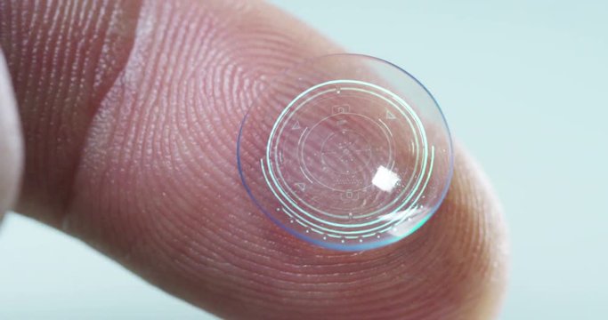 Macro shot of a finger holding a contact lens technology with a chip to see better in both eyes and increase diopters. Concept: eye examination, optical, immersive technology