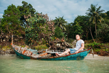 Fototapeta na wymiar Man siting on boat near tropical island