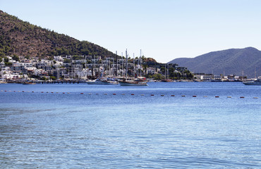 Fototapeta premium Luxury yachts and sail boats parked in front of Bodrum - Icmeler city in a sunny summer day. The city is on the Bodrum Peninsula, stretching from Turkey's southwest coast into the Aegean Sea.