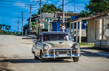 HDR - Brauner Oldtimer mit schwarzem Dach fährt durch die Vorstadt in Havanna Kuba - Serie Kuba Reportage