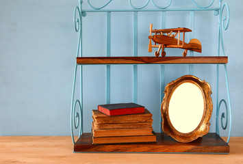Vintage shelf with old wooden plane toy, books and blank photo frame