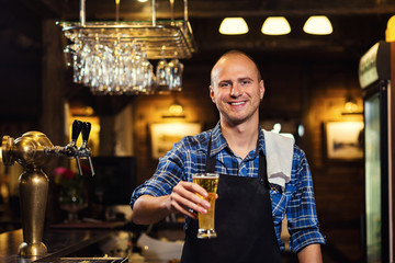 Bartender pouring the fresh beer in pub,barman hand at beer tap pouring a draught lager beer,beer from the tap,Filling glass with beer,fresh beer,pub.Bar.Restaurant.European bar.American bar.