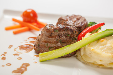 Medallions of grilled veal with gratin potatoes close up