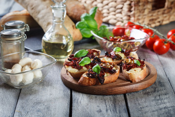 Appetizer bruschetta with sun-dried tomatoes, olives and mozarella.