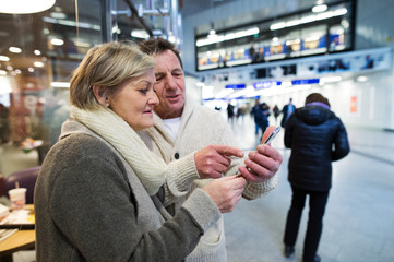 Senior couple with smartphone in hallway of subway