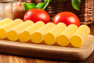 Uncooked cannelloni pasta on cutting board and ingredients