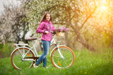 Obraz premium Female cyclist with vintage white bicycle in spring garden