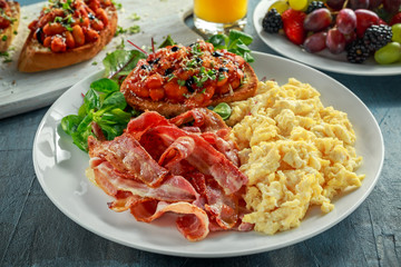 Morning Scrambled egg, bacon breakfast with beans in tomato sauce on toasted bread on white plate