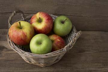 Basket of fresh apples on wooden background