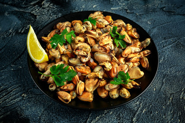 Seafood. Steamed Musseles appetizer with sprinkle of parsley and lemon juce served on black plate.