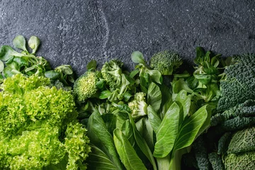 Photo sur Plexiglas Légumes Variété de salades de légumes verts crus, laitue, bok choy, maïs, brocoli, chou de Savoie comme cadre sur fond de texture en pierre noire. Vue de dessus, espace pour le texte