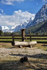 Landscape of Dolomites mountains in summer with a fountain near a fence