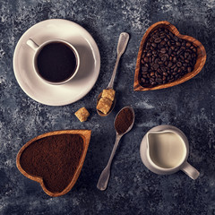 Coffee cup, beans and ground powder on stone background.