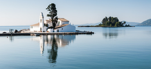 The church of Panagia Vlacherna and the island of Pontikonissi (mouse island) on a quiet tranquil morning. - obrazy, fototapety, plakaty