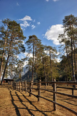 Landscape of Dolomites mountains in summer with a farm and meadows near a fence