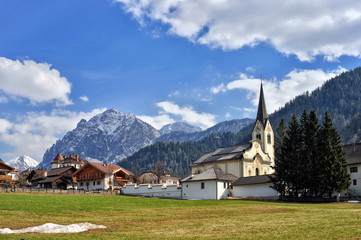 Landscape of Dolomites mountains in summer with a typical village and meadows