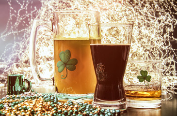 St Patricks Day Pub Alcohol. Saint Patrick's Day pub items, including a large mug of beer, a glass of Irish stout, and a shot of Irish Whiskey neat. Set against a celebration lit background.
