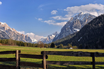 Fototapeta na wymiar Landscape of Dolomites mountains in summer with a farm and meadows near a fence