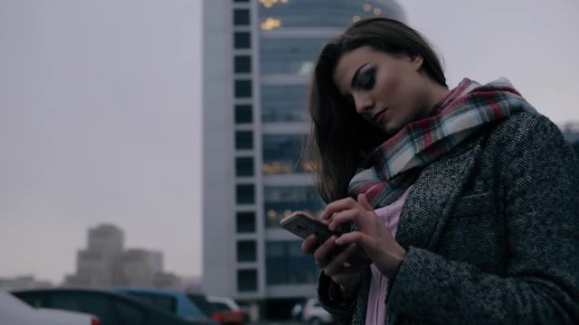 Young woman looking down to smart phone in downtown