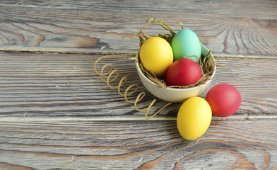 Пасхальные цветные яйца находятся на деревянном столе.