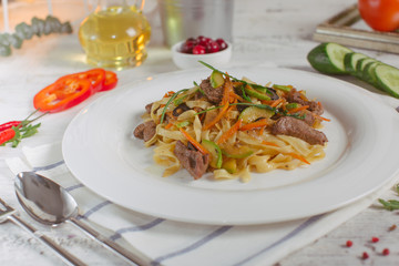 Pasta with olive meat greens on a white plate