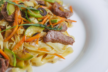 Pasta with olive meat greens on a white plate